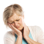 older woman suffering from toothache holding her jaw
