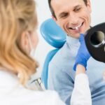 man looking at dental implant smiling in mirror
