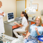 smiling patient in dental chair with dentist and dental assistant behind her