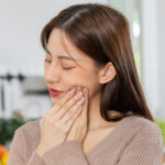 young woman having tooth pain holding her hand to her cheek