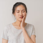 young woman with tooth pain holding her cheek
