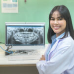 A female dentist working with teeth x-ray on laptop in dental clinic