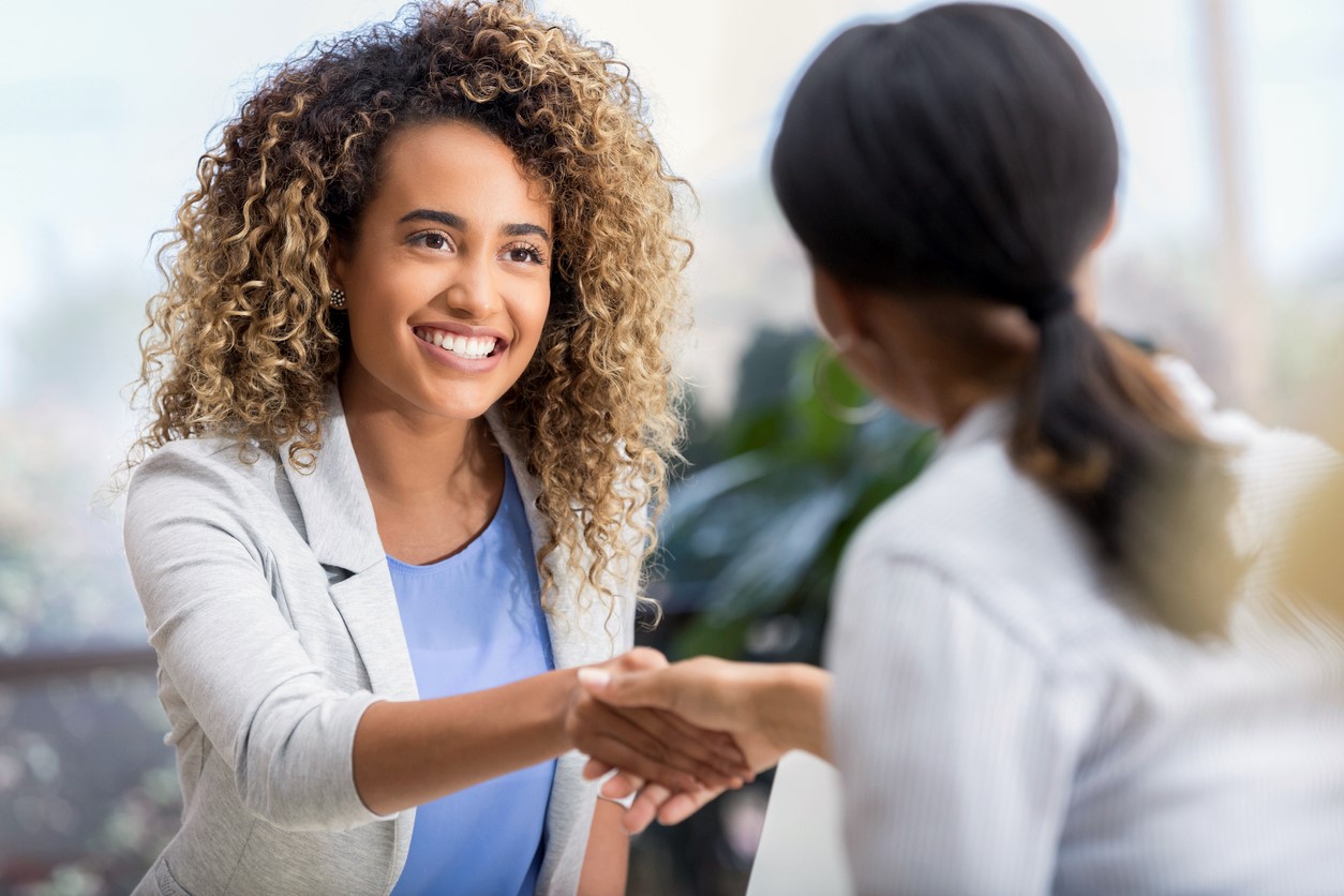 two women in business attire shaking hands