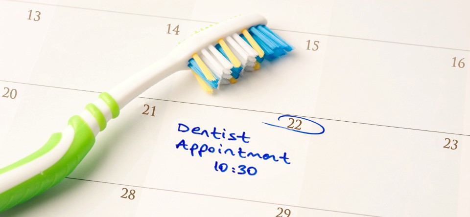 tooth brush laying on a calendar with a dental appointment note on it